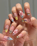 Close-up of star rhinestones and hand-painted French tips on almond-shaped press-on nails.