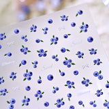 3D blueberry French tip nail stickers sheet and realistic fruit nail art application on a model's hands. Perfect DIY press-on gel nails featuring sweet textured blueberry decals, trendy white polka-dot French tips, and delicate bows for a summer coquette aesthetic.