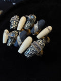 A close up of luxury designer press on nails featuring iconic Dior nail art.