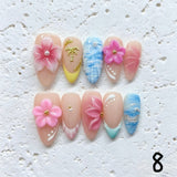 Amourwa luxury handmade 3D flower and gold palm tree press-on nails display. Features gorgeous pastel pink and yellow French tip nails decorated with large 3D floral designs, textured blue ocean marble nail art, and realistic clear water droplets for a summer beach vacation holiday manicure.