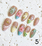 Amourwa luxury handmade 3D flower press-on nails display. Features elegant pastel pink and green gradient almond nails decorated with intricate 3D embossed floral designs, white abstract swirls, and trendy gold French tip accents for a summer coquette aesthetic manicure.